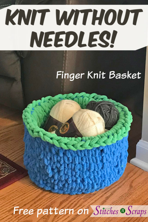 A fuzzy, finger knit basket in bright blue and green, on a wood floor next to a beige wall, brown couch, and red rug. Basket is filled with skeins of yarn. Knit Without Needles! - Finger Knit Basket - Pattern on Stitches n Scraps