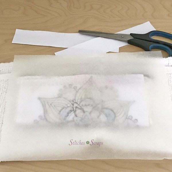 A silicone sheet, over a pencil case wrapped in paper with a mandala design, on top of a white towel, on a wood table. In the background are scissors and paper scraps. Personalized Pencil Case on Stitches n Scraps