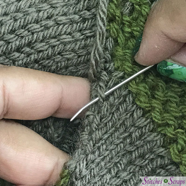 Taupe and green striped fabric. Hands inserting a yarn needle through a loop a the edge of one piece.