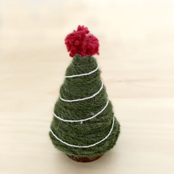 A yarn wrapped wooden tree decorated with silver thread and a red pom pom