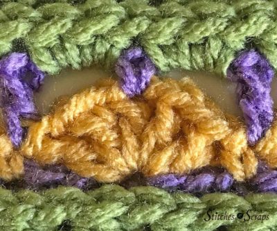 Crochet swatch showing a fan stitch in yellow, with green and purple stitches around it. Supernova Square on Stitches n Scraps