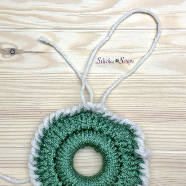 A loop of yarn on top of a crocheted mini christmas wreath