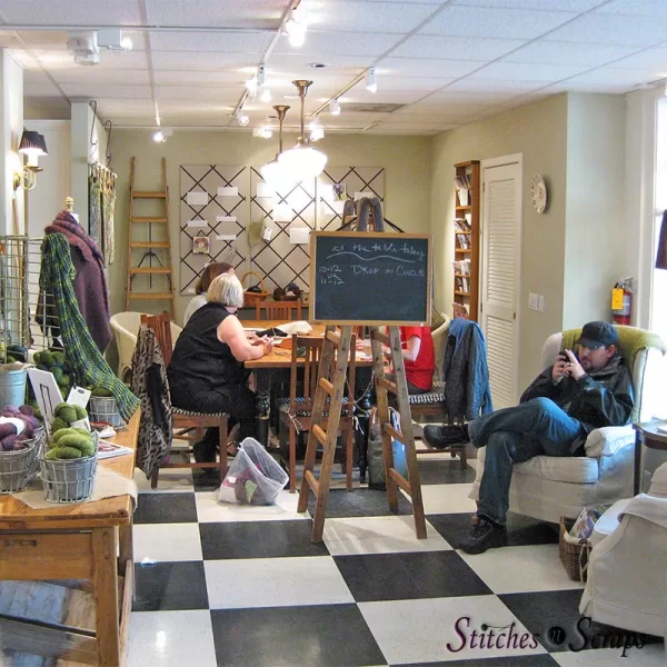 people working at the work table while another person rests on a comfy chair