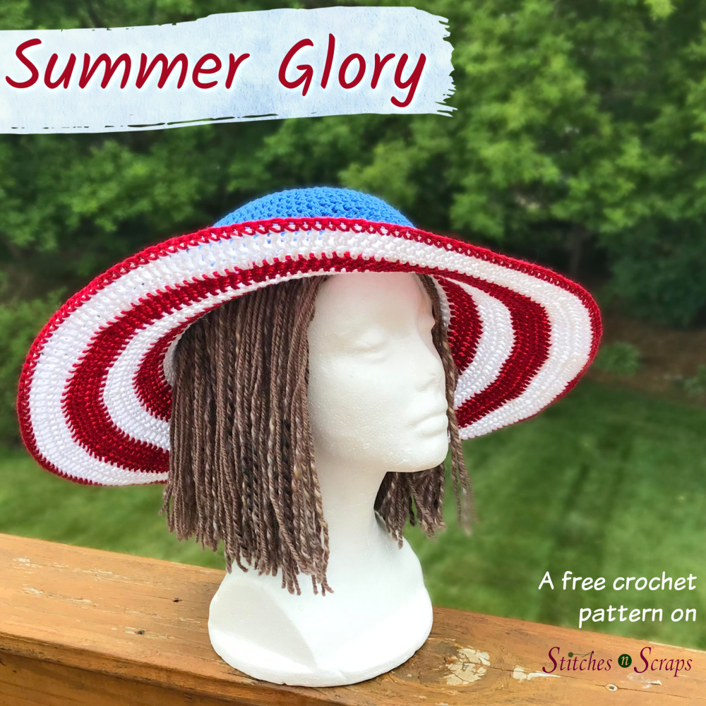 Summer Glory Sun Hat - a free pattern on Stitches n Scraps. Sun hat with red and white striped brim and blue crown on a foam head with brown yarn "hair". Head is placed on a wood railing overlooking trees and grass.