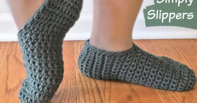 Woman's ankles and feet, wearing Simply Slippers. One foot is flat on the wood floor, the other is up on the toe and turned sideways. Simply Slippers - free crochet pattern on Stitches n Scraps