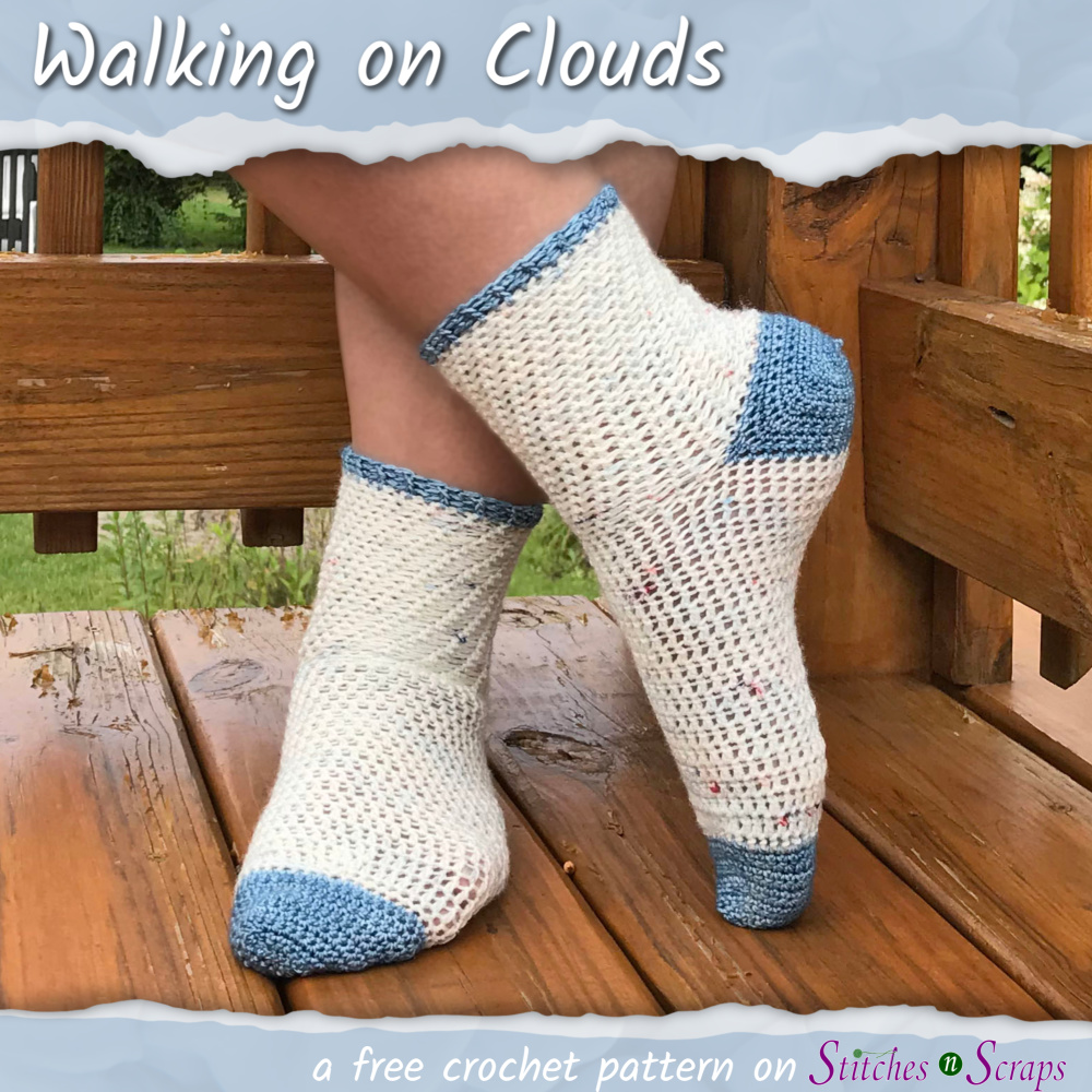 Two feet, standing crossed on a wood deck with a wood rail. The feet are wearing white socks with blue toes, heels and cuff edging. Wording reads Walking on Clouds - a free crochet pattern from Stitches n Scraps