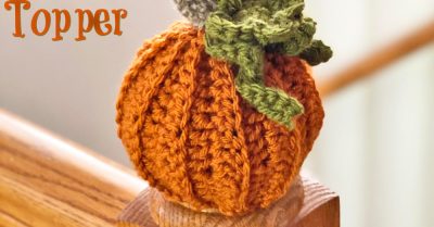 A stair rail post with a round knob that has a crocheted pumpkin cover on it. Text says Pumpkin Post Topper - a free crochet pattern on Stitches n Scraps
