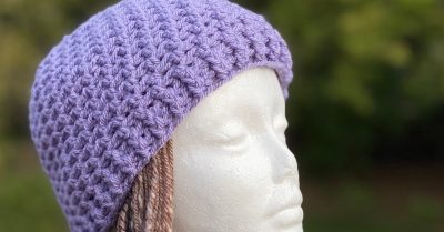 A foam mannequin head with brown hair, wearing a lavender crochet beanie. Text says "Pearson - crochet hat pattern on Stitches n Scraps"