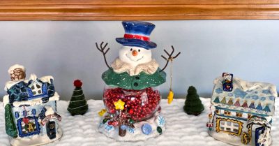 A finger knit snow blanket, with some holiday decorations on top of it. Text - Finger Knit Snow Blanket - Free Pattern on Stitches n Scraps