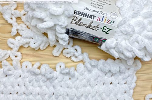 a finger knit swatch with a skein of Bernat Blanket EZ yarn. Text - Twisted Stitches in Loop Yarn, Finger Knitting Tutorial on Stitches n Scraps