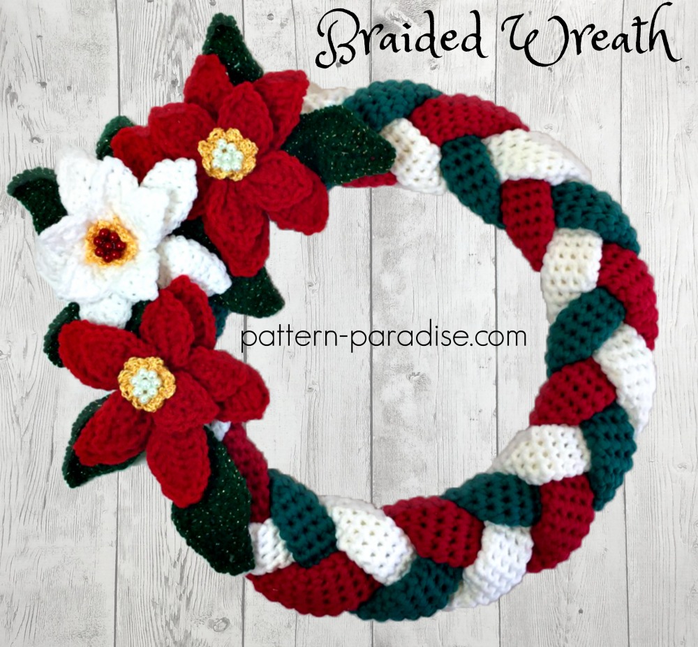 A wreath made of braided strips of crochet with poinsettias on it. Braided Christmas Wreath from Pattern Paradise