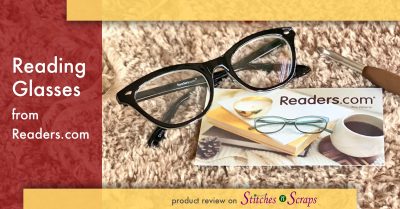 Reading glasses from readers.com, on a fur yarn background, next to a readers.com business card and a crochet hook.