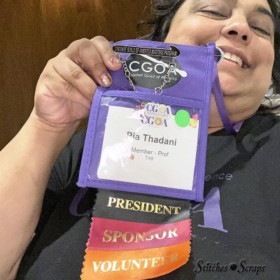 Me holding up my Chain Link 2022 name badge, with President, Sponsor, and Volunteer ribbons attached